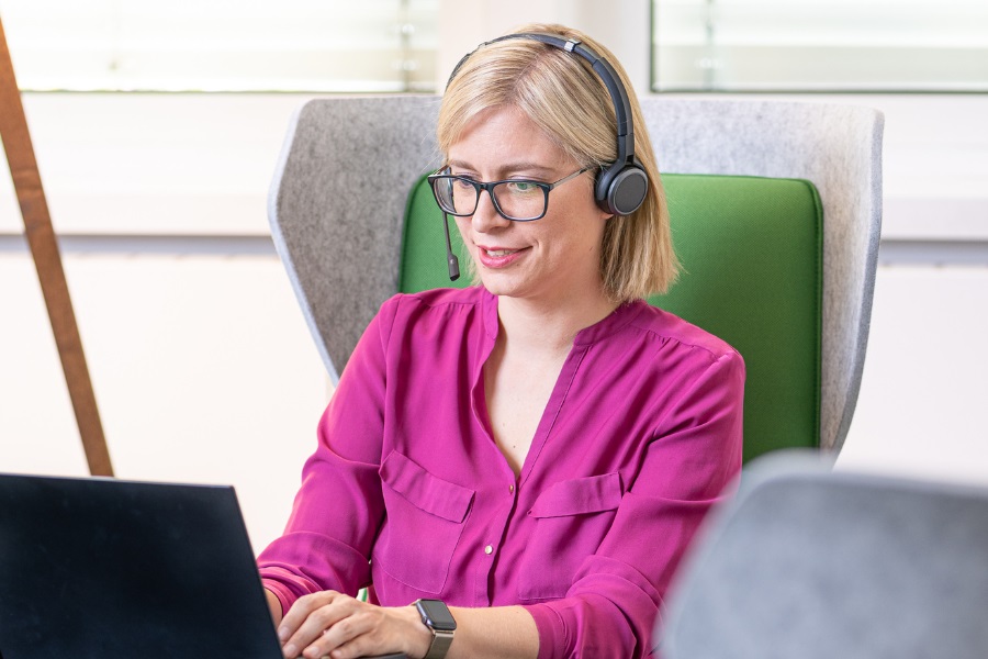 Frau an Laptop mit Kopfhörern